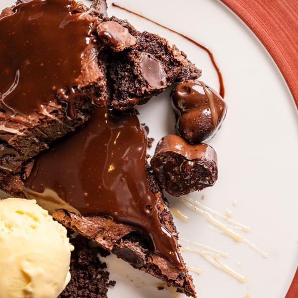 Rich chocolate brownies with melted chocolate, heart-shaped chocolates, and a scoop of vanilla ice cream.