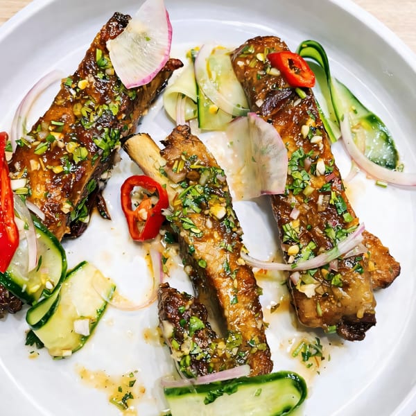 Three glazed ribs with herbs, chopped nuts, red chilies, cucumber ribbons, and radish slices.